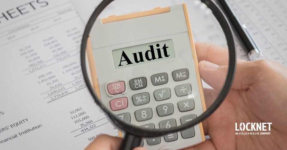 An image of financial papers spread out on a table with a magnifying glass looking at then with the word “Audit” in the center.