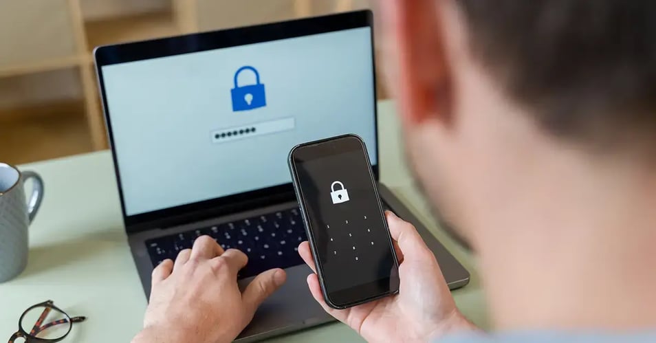 an image of an employee going through the MFA process on his phone while logging into an application on his laptop