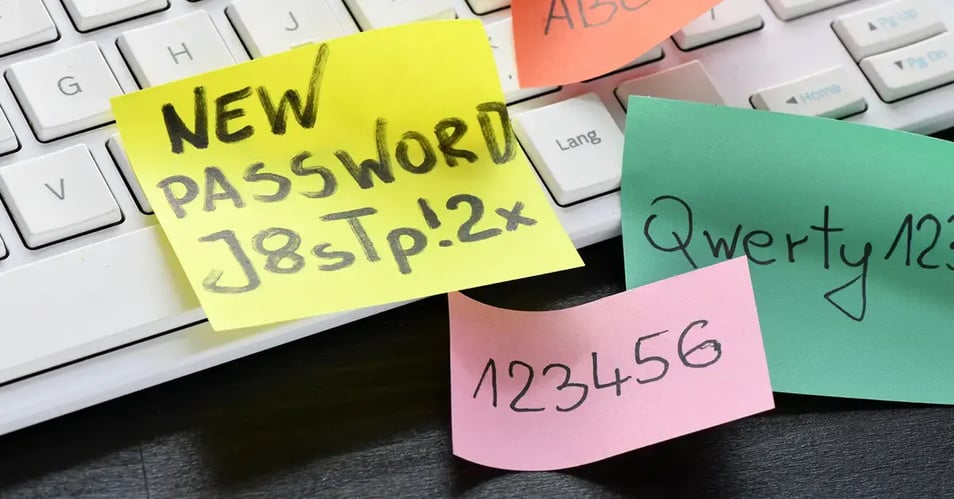 Sticky notes with weak passwords on a keyboard, illustrating common examples of cybersecurity risks caused by poor employee credential management.