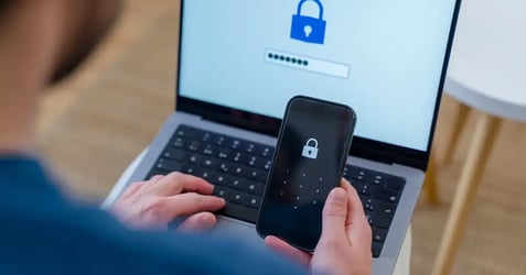 A person using a smartphone and laptop for multi-factor authentication, illustrating identity management in a Zero Trust security framework.