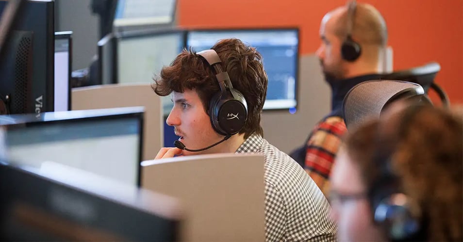 IT support technicians wearing headsets at their computers, illustrating managed IT services and key person risk management for community banks.