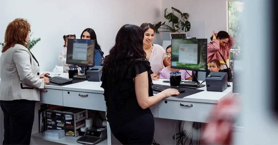 Bank staff helping customers at a busy service counter, reflecting the daily demands behind managed IT backlogs